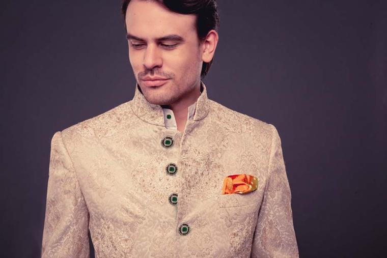 A sherwani by fashion designer Raghavendra Rathore featuring diamond and emerald buttons.